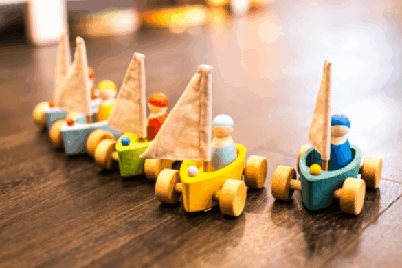 Wooden-Sailboat-Toys Colourful wooden sailboat toys with small figurines lined up on the floor